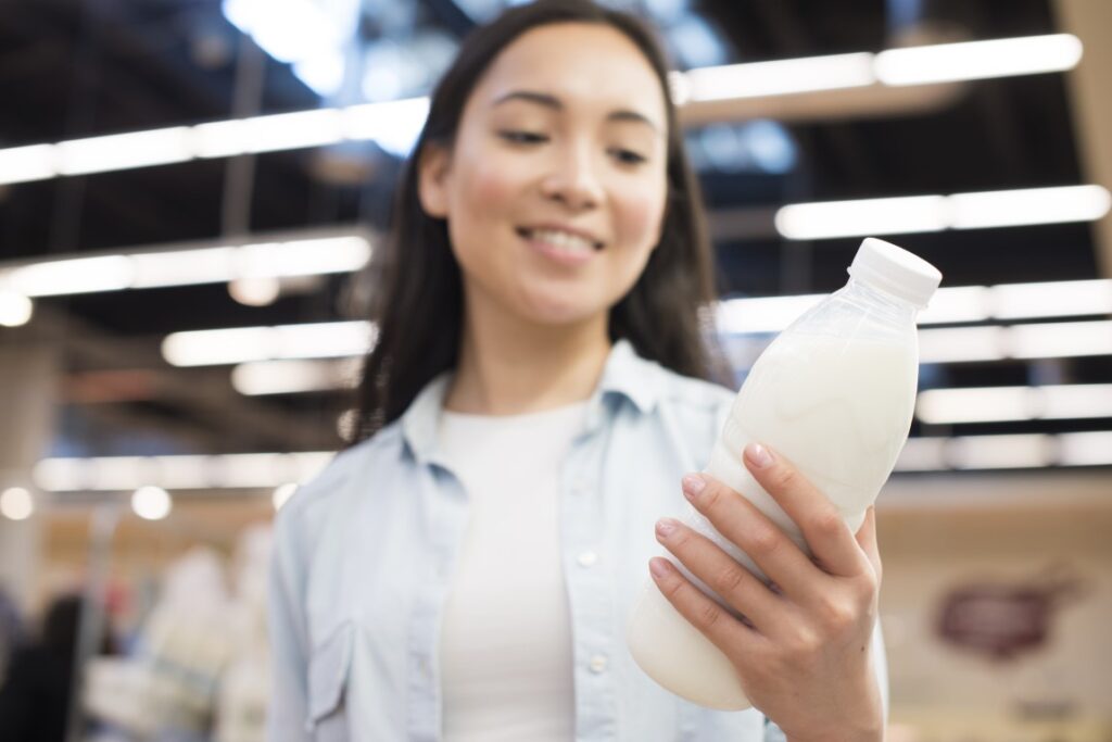 cheerful-asian-female-holding-bottle-milk-supermarket