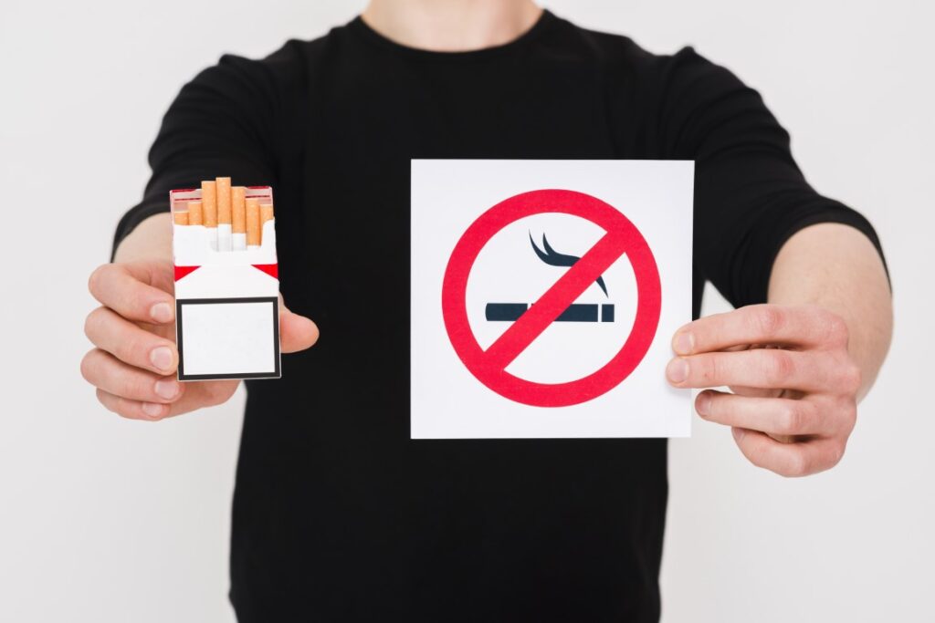 man-holding-cigarettes-packet-no-smoking-sign-white-background