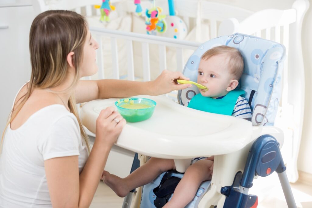young-woman-feeding-her-baby-from-spoon-with-apple-sauce